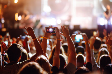 Using a smartphone in a public event, live music festival. Holding a mobile phone in hands and...