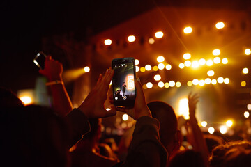 Using a smartphone in a public event, live music festival. Holding a mobile phone in hands and...