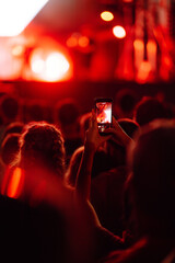 Using a smartphone in a public event, live music festival. Holding a mobile phone in hands and...