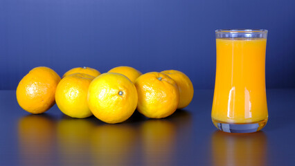 Close-up and vivid studio shot, a glass of orange juice, and a group of natural fresh oranges on...