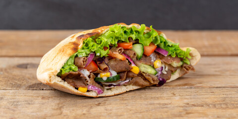 Döner Kebab Doner Kebap fast food in flatbread on a wooden board panorama