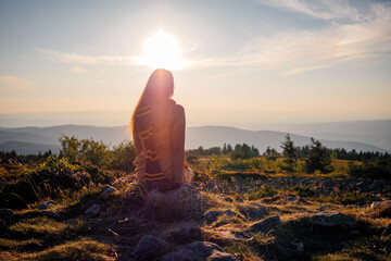 Femme devant un coucher de soleil au sommet