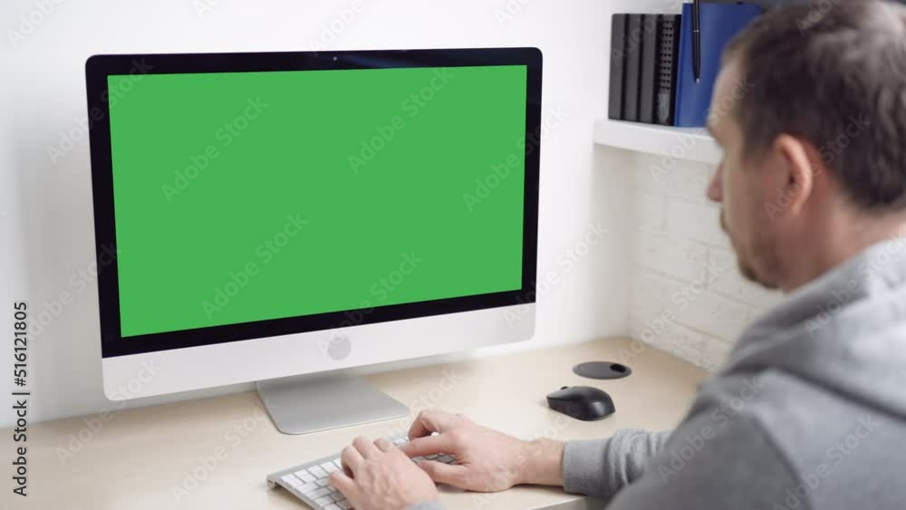 Aufkleber man sitting at the workplace typing on keyboard computer with green screen minimalist workplace at home or office