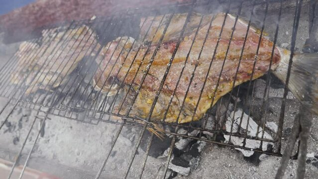 A dorade, gilt-head bream, sea bream fish is being grilled in a street restaurant in Morocco. Fresh seafood background, 4k footage.