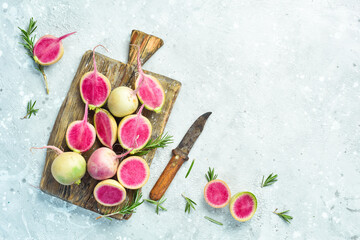 Sliced radish watermelon on the kitchen board. Dietary useful vegetables. On a gray stone background.