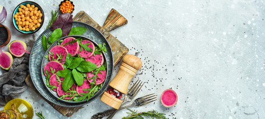 Fresh healthy salad: spinach, radish watermelon, black sesame and olive oil. Healthy food. Top view. On a stone background.