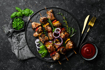 Traditional Kebab. Juicy pork skewers with vegetables on a black stone plate. Barbecue. Top view....