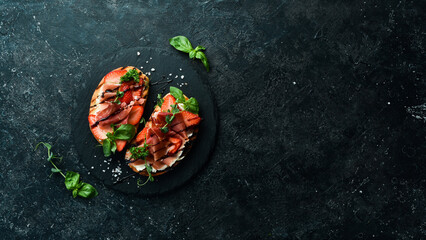 Sandwich with cheese, prosciutto, strawberries and basil. Bruschetta. Top view. On a stone...