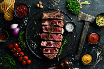 Veal steak on a bone. Juicy pieces of steak. Free space for your text. Top view. On a black stone...