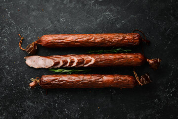 Delicious salami sausage with spices and rosemary. On a black stone background. Top view. Free...