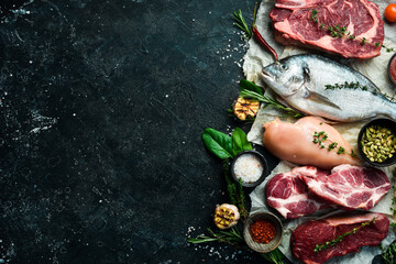 Various protein sources concept - rib eye, dorado, pork, egg. Top view. On a black stone background.