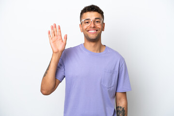 Young caucasian Brazilian man isolated on white background saluting with hand with happy expression