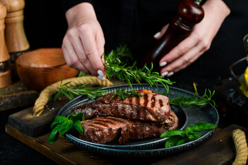 Grilled ribeye beef steak, herbs and spices on a dark table. Top view. Free space for your text.