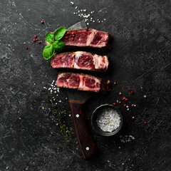 Veal steak on the knife. Grill steak. Free space for your text. On a black stone background.