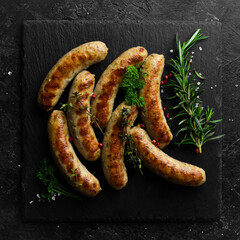 Juicy grilled sausages with turkey meat. Barbecue. On a black stone background.