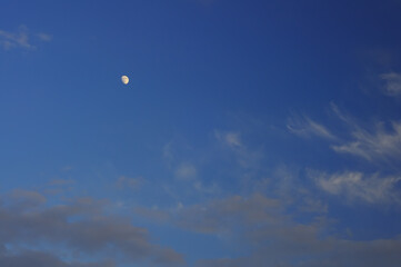 Real photo of the sky at dusk, light clouds and the moon. Focus around the frame