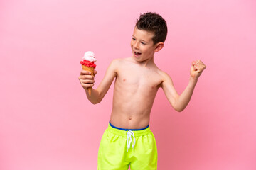 Little caucasian boy eating an ice-cream isolated on pink background celebrating a victory