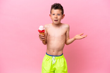 Little caucasian boy eating an ice-cream isolated on pink background with shocked facial expression