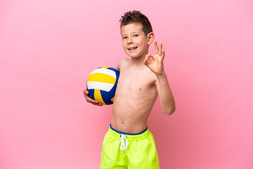 Little caucasian boy playing volleyball isolated on pink background showing ok sign with fingers