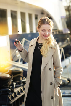 young blond beautiful woman with long hair wearing trench coat closeup street portrait
