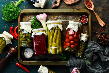 Homemade pickled vegetables in a glass jar. Food supplies. On a stone background. Top view.