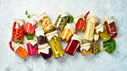 Jars with different vegetables on a stone background. Marinated vegetables. Food stocks in case of crisis. On a stone background. Top view.