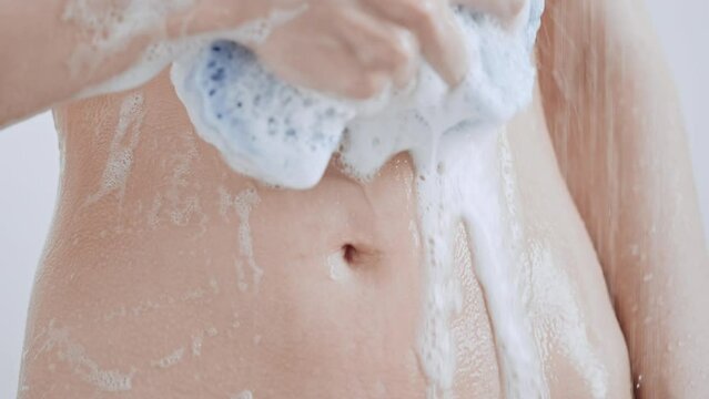 unrecognizable caucasian woman take shower foam flows down the slim stomach slim female with athletic body take a bath
