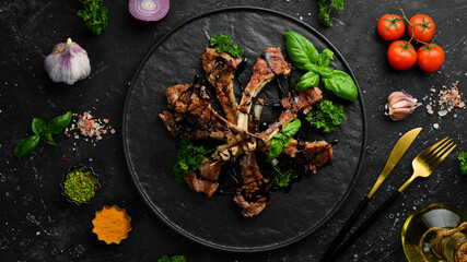 Roasted lamb ribs with spices and garlic on a dark kitchen table. Rustic style. Photo for the catalog. © Yaruniv-Studio
