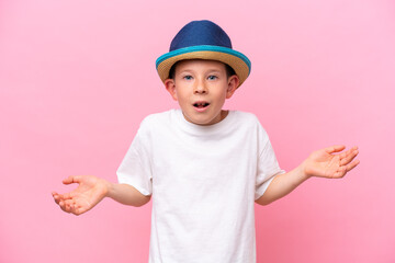 Little caucasian boy wearing a hat isolated on pink background with shocked facial expression