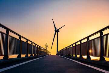 夕暮れ時の静岡県掛川市の菊川河口にある自転車道の潮騒橋と風力発電の風車
