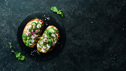Vegan Sandwich with radish, cucumber, cheese and basil. Bruschetta. Top view. On a stone background.