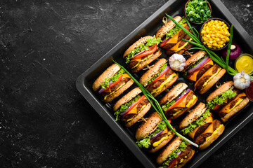 Delicious grilled homemade burgers with beef, tomatoes, cheese, onions and salad. Burger menu. Top view. On a black stone background.