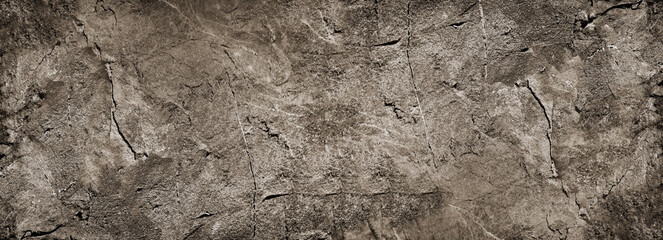 Dark gray brown rock texture. Rough mountain surface with cracks and scratches. Close-up. Grunge. Stone granite background with space for design. Backdrop. Web banner. Wide. Panoramic.
