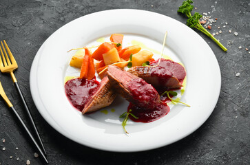 Baked duck breast with celery root and vegetables on a white plate. Top view. Rustic style.
