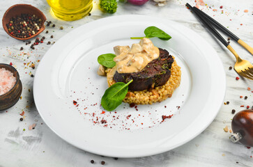 Beef steak with bulgur and mushrooms on a plate. Restaurant menu. European cuisine.