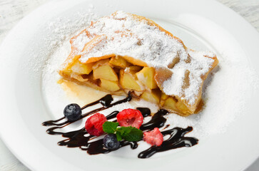 Dessert. Apple strudel with berries and chocolate on a plate. Top view.