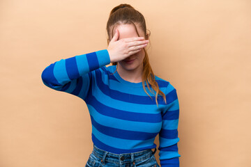 Young caucasian woman isolated on beige background covering eyes by hands. Do not want to see...
