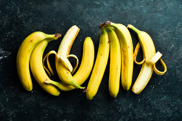 Tropical bunches of yellow bananas on a black stone background. Top view.