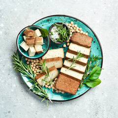 Tofu cheese. Organic Tofu soy cheese with rosemary cut into pieces on a plate. On a stone background.