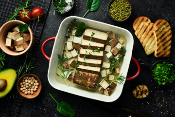Tofu cheese. Baked Tofu cheese with rosemary and spices in a bowl. On a stone background.
