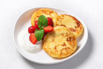 Cottage cheese pancakes with strawberries on a gray background. Side view.