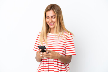 Fototapeta premium Blonde Uruguayan girl isolated on white background sending a message with the mobile