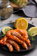 Shrimps on stone background. Grilled prawns with rosemary and lemon. 