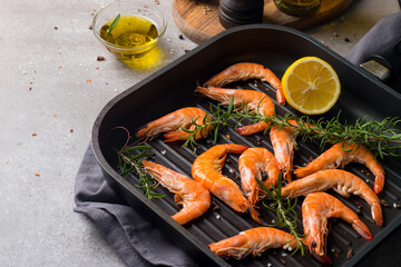 Shrimps on stone background. Grilled prawns with rosemary and lemon. 