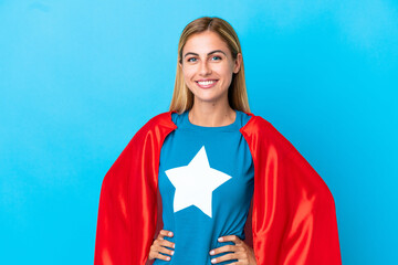 Blonde woman over isolated background in superhero costume posing with arms at hip and smiling © luismolinero