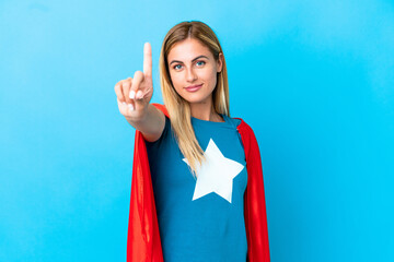 Blonde woman over isolated background in superhero costume and pointing to the front
