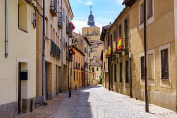 Narrow alley with old houses and view of the cathedral of Segovia in the background, Spain.