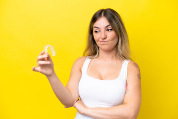Young Rumanian woman holding envisaging isolated on yellow background with sad expression