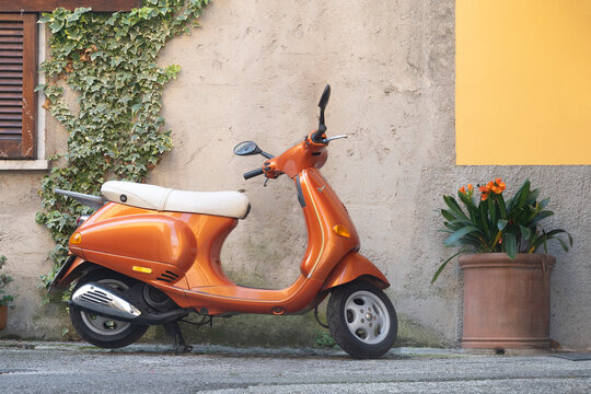 Modern orange Vespa Piaggio parked in an Italian alley