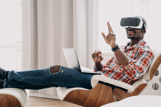 African freelancer in vr headset enjoying the vision at home. Businessman has virtual meeting.
